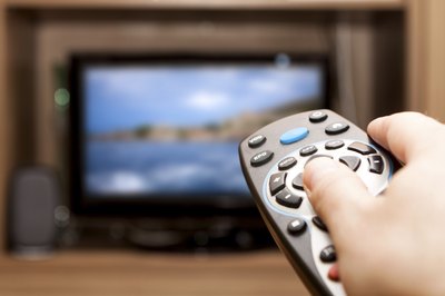A close-up of a person using a remote to adjust a television.