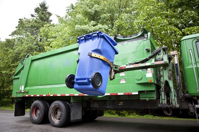 A gabage truck picks up a trash can.