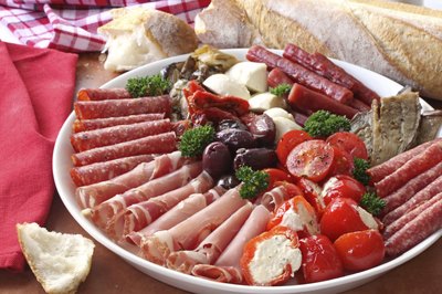 Antipasto platter with meats, cheeses, and breads on table.