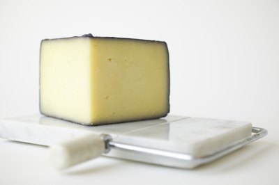 A wedge of cheese on a cutting board.