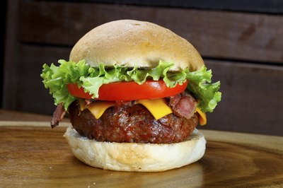 A hamburger with cheese, lettuce and tomato on a bun.