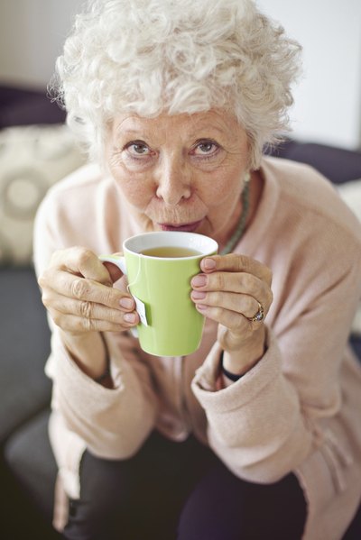 A woman sips a cup of hot tea.