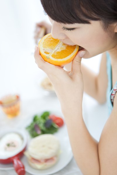 A woman is biting into an orange.