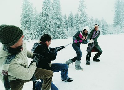 Friends playing a game of tug-of-war in the snow.