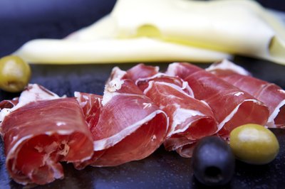 Prosciutto on plate beside cheese