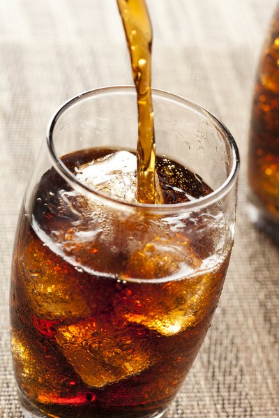 Soda being poured into a glass with ice
