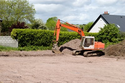 A bulldozer begins the construction process on an empty lot.