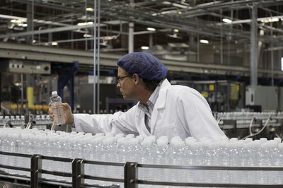 An employee in a bottled water plant inspects the products.