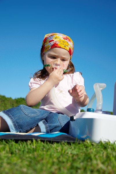 Young girl using nebulizer outdoors