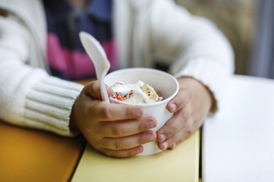Hands of a toddler holding a cup of yogurt.