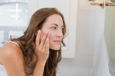Woman examining her face in the mirror.