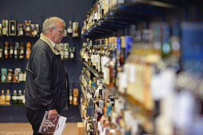 Man admires bottles of whiskey at auction
