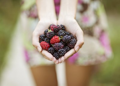 A young woman is holding a handful of berries.