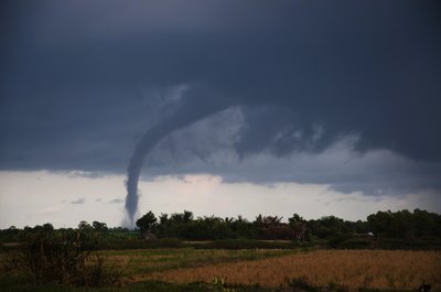 A tornado forms and moves across the ground in the distance.