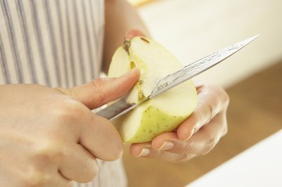 Close-up of woman slicing an apple.