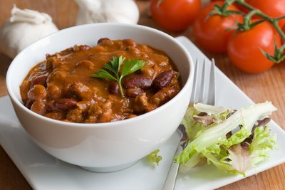 Bowl of chill with a garnish of lettuce.