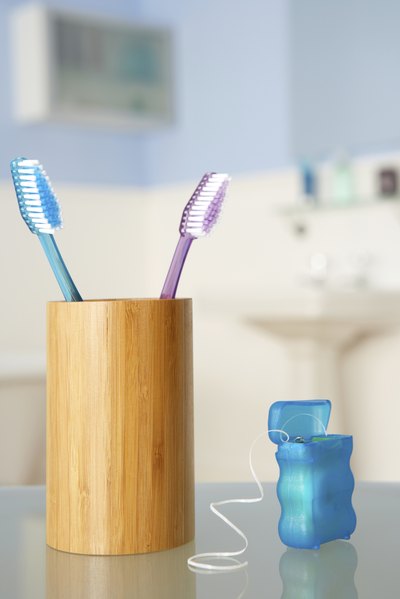 A close-up of dental floss next to a toothbrush holder.