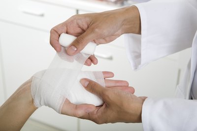 A doctor applies a bandage to a patient's palm.