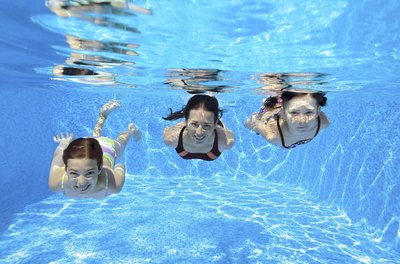 Three young girls swim in a pool.