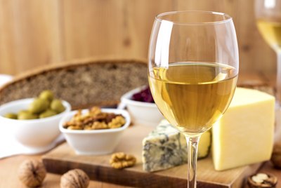 Wine glass with cheese and nuts in background