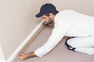 A worker installing wall-to-wall carpeting.
