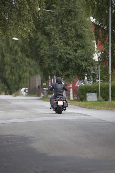 A man rides low on a motorcycle with a wide rear tire.