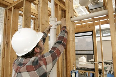 A home builder connects pipes.