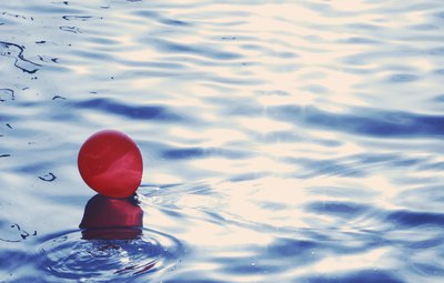 A red balloon floating on water.