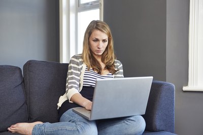 A young woman is browsing on her laptop.