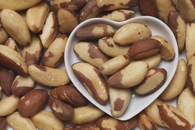 Brazil nuts in a heart shaped bowl and covering a table.