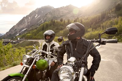 A couple tours the countryside on motorcycles.