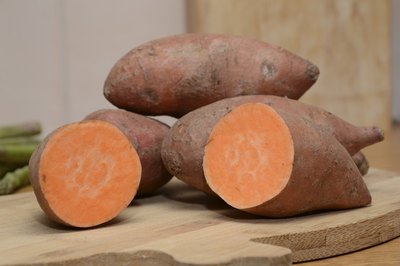 A halved sweet potatoe on a cutting board.