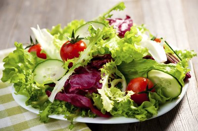 A plate of salad on a wooden table.