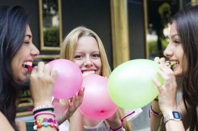 Girls blowing up balloons at birthday party.