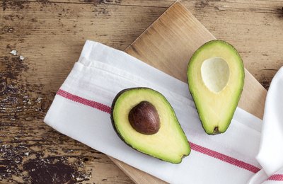 Halved avocado on cutting board.