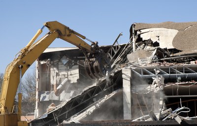 An excavator destroys a building.