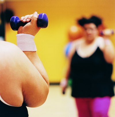 A woman does weight training at a gym.