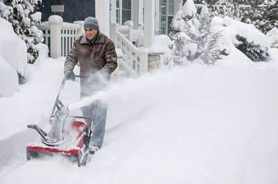 A man clearing his driveway using a single-stage snowblower