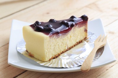 A slice of blueberry cheesecake on a wooden table.