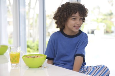 Child sitting beside bowl of cereal.