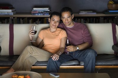 A couple watching tv and drinking wine