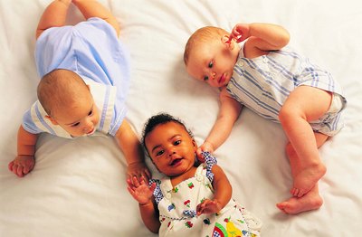 3 infants lay on a blanket together.