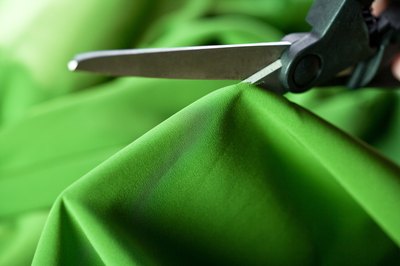 Scissors cutting green fabric