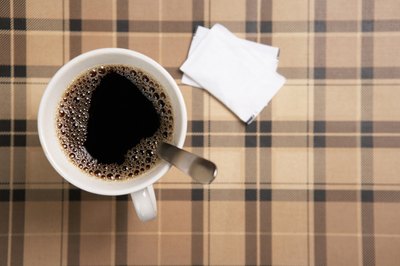 A cup of coffee with sugar packets.