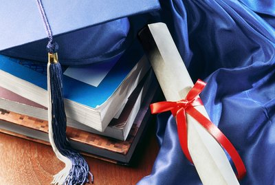 A close-up of a diploma, tassle, and books.