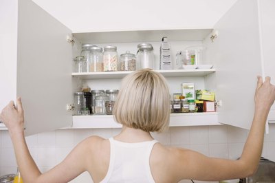 Woman opens kitchen cabinets with both hands.