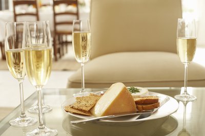 Assortment of cheeses beside glasses of white wine.