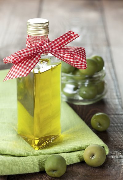 A bottle of olive oil with a gingham ribbon on a rustic table.