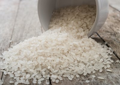 Uncooked white rice spilling from bowl