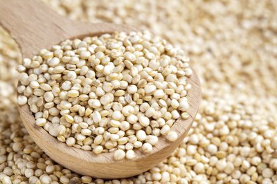 A wooden spoon filled with quinoa.
